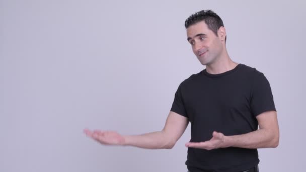 Happy handsome man showing something against white background — Stock Video