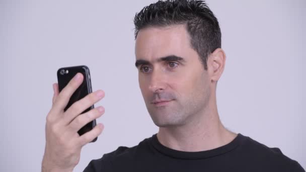 Primer plano del hombre guapo usando el teléfono contra el fondo blanco — Vídeo de stock