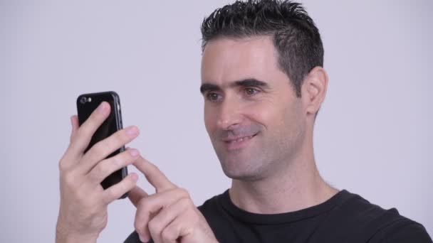 Крупный план счастливого красавца, использующего телефон на белом фоне — стоковое видео