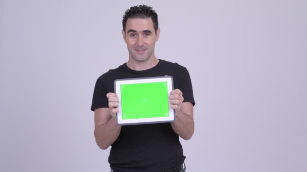 Счастливый красивый мужчина показывает цифровой планшет на белом фоне — стоковое видео