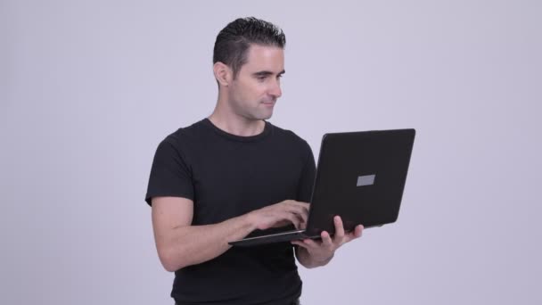 Stilig man använder laptop mot vit bakgrund — Stockvideo