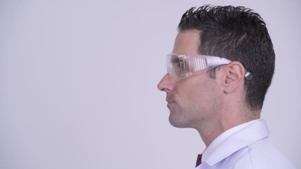 Vista del perfil de la cabeza del médico hombre feliz con gafas protectoras mirando a la cámara — Vídeo de stock