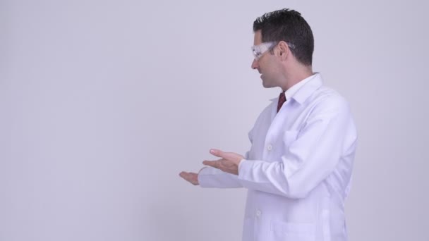 Щасливий красивий чоловік лікар з захисними окулярами показує щось — стокове відео