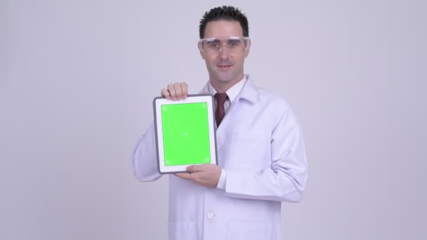 Feliz hombre guapo médico con gafas protectoras que muestran tableta digital — Vídeos de Stock