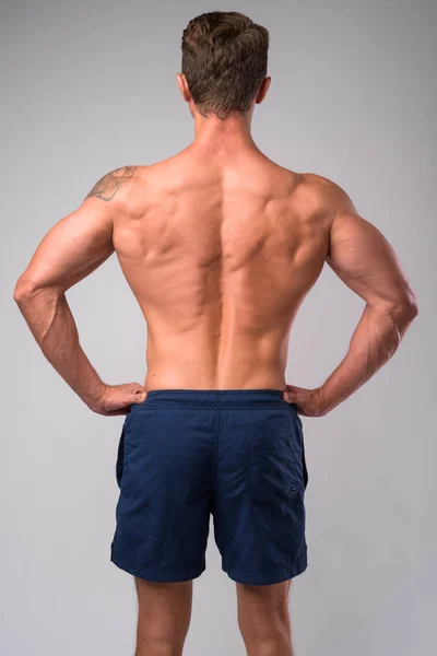 Visão traseira do homem muscular sem camisa com as mãos nos quadris — Fotografia de Stock