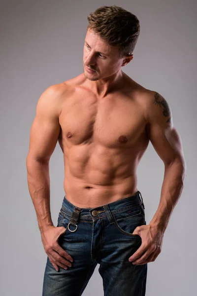 Muscolare bell'uomo barbuto senza maglietta contro sfondo bianco — Foto Stock