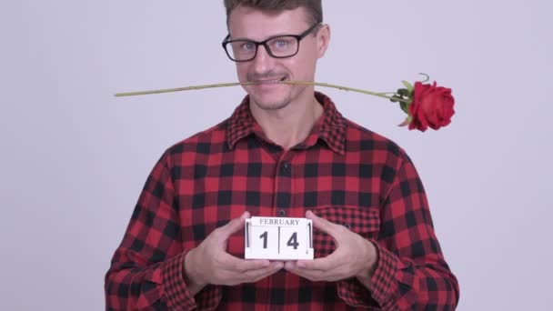 Homem hipster barbudo feliz segurando bloco de calendário pronto para o dia dos namorados — Vídeo de Stock