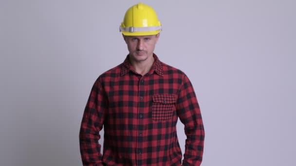 Feliz barbudo trabajador de la construcción sonriendo sobre fondo blanco — Vídeo de stock