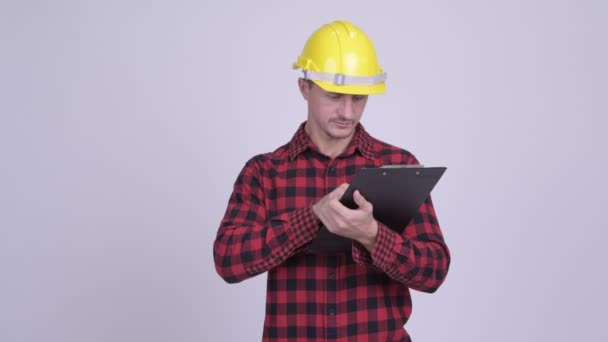 Feliz barbudo trabajador de la construcción leyendo en el portapapeles y dirigiendo — Vídeos de Stock