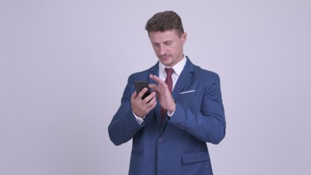 Knappe bebaarde zakenman denken tijdens het gebruik van de telefoon — Stockvideo