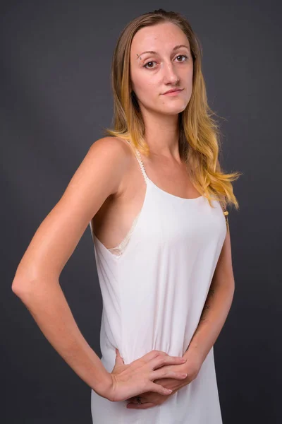 Junge schöne Frau mit glatten blonden Haaren gegen grauen Rücken — Stockfoto