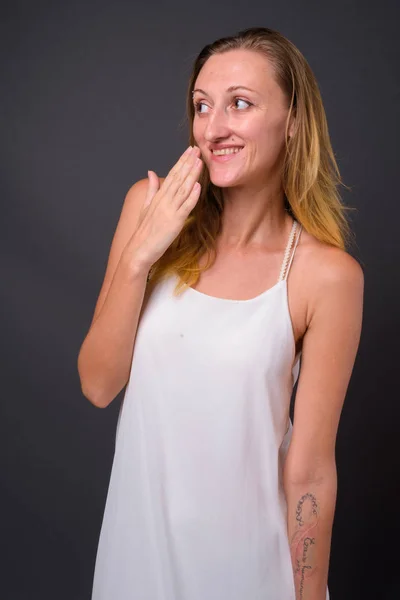 Jovem mulher bonita com cabelo loiro liso contra costas cinza — Fotografia de Stock