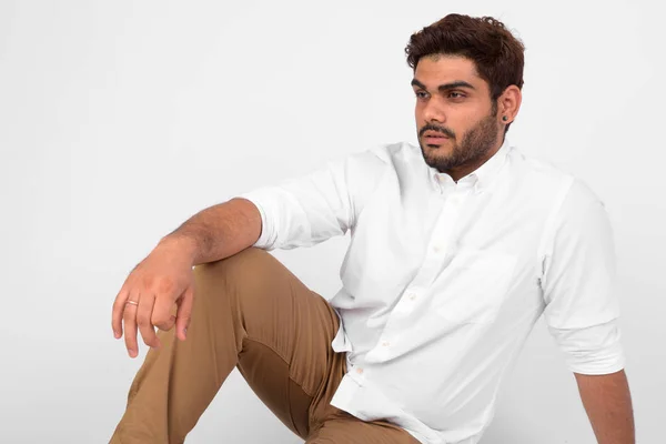 Young handsome bearded Indian man thinking and sitting on the floor — Stock Photo, Image