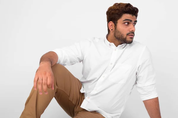 Junger schöner bärtiger indischer Mann sitzt auf dem Boden und denkt — Stockfoto