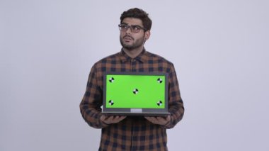Dizüstü bilgisayarı gösteren süre düşünerek mutlu genç Hintli hipster adam