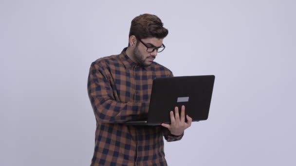 Jovem barbudo indiano hipster homem pensando ao usar laptop — Vídeo de Stock