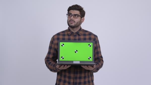 Dizüstü bilgisayarı gösteren süre düşünerek mutlu genç Hintli hipster adam — Stok video
