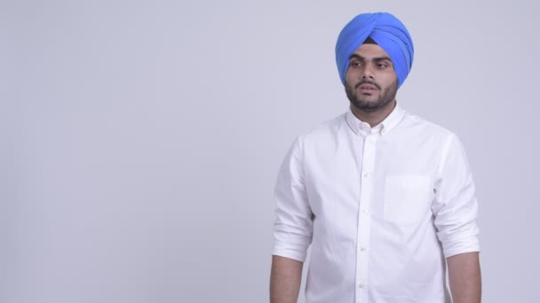 Glada unga skäggig indisk Sikh man tänker samtidigt pekar uppåt — Stockvideo