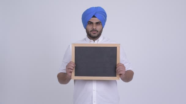 Happy young bearded Indian Sikh man holding blackboard — Stock Video