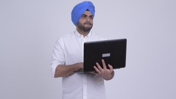 Młody Brodaty Indian Sikh człowiek myśli podczas korzystania z laptopa — Wideo stockowe