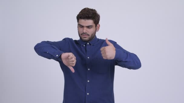 Jonge, bebaarde Indiase zakenman kiezen tussen duimen omhoog en de duim omlaag — Stockvideo