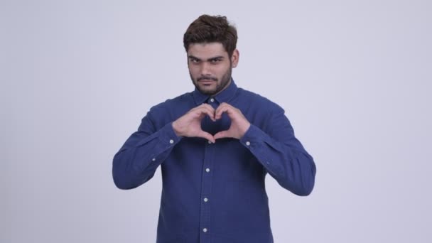 Happy young bearded Indian businessman with hand heart gesture — Stock Video