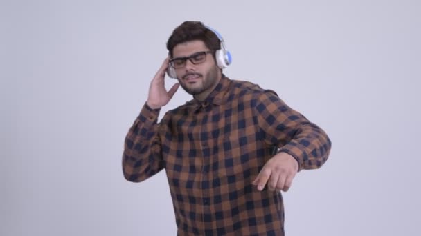 Happy young bearded Indian hipster man listening to music — Stock Video