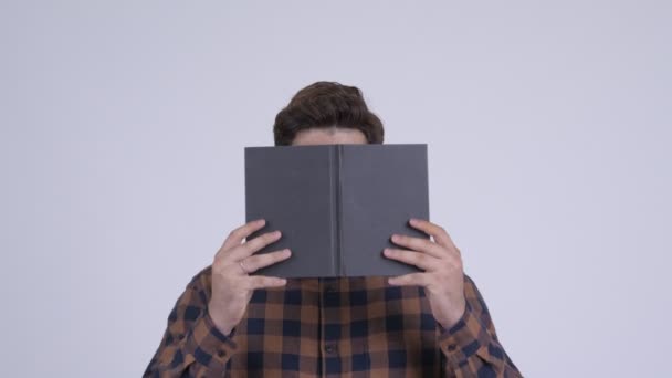 Young Indian hipster man covering face with book — Stock Video