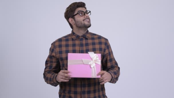 Feliz joven barbudo hipster indio hombre sosteniendo caja de regalo y pensando — Vídeos de Stock