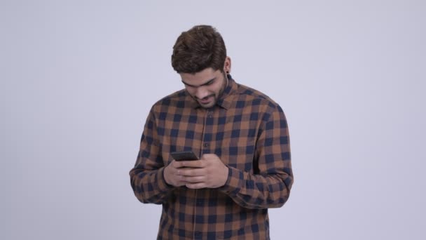 Young bearded Indian hipster man thinking and using phone — Stock Video