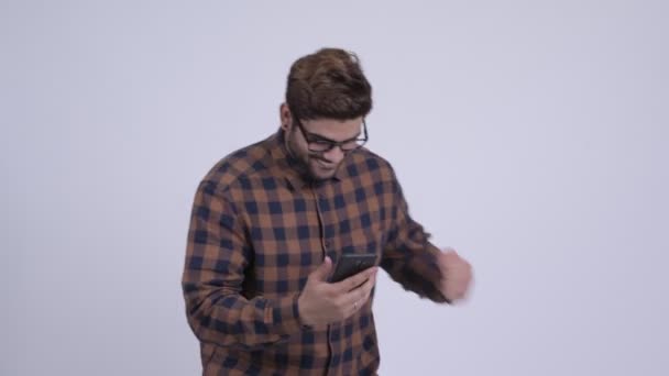 Feliz joven barbudo hipster indio hombre usando el teléfono y recibiendo buenas noticias — Vídeo de stock