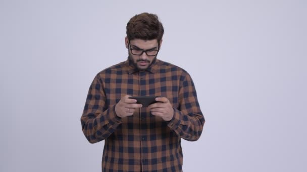 Stressed young bearded Indian hipster man using phone and getting bad news — Stock Video