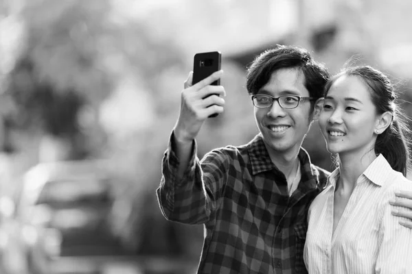 Pasangan muda Asia mengambil selfie luar ruangan dalam warna hitam dan putih — Stok Foto