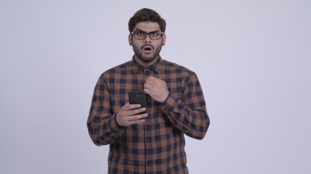 Glad ung skäggig indisk hipster man använder telefonen och letar efter förvånad — Stockvideo