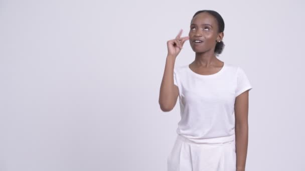 Счастливая молодая красивая африканская женщина думает, указывая вверх — стоковое видео