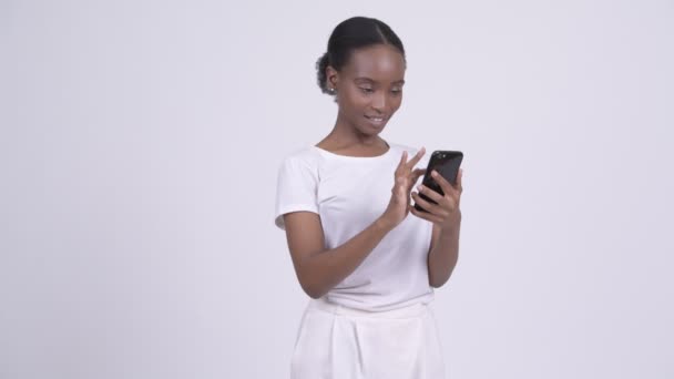 Jovem feliz bela mulher africana usando telefone e recebendo boas notícias — Vídeo de Stock