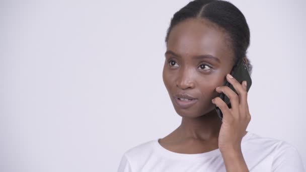 Rosto de feliz jovem bela mulher africana pensando ao falar ao telefone — Vídeo de Stock