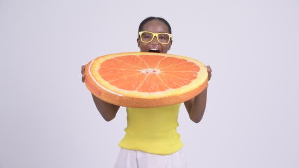 Joven mujer africana feliz mordiendo almohada naranja como concepto saludable — Vídeo de stock