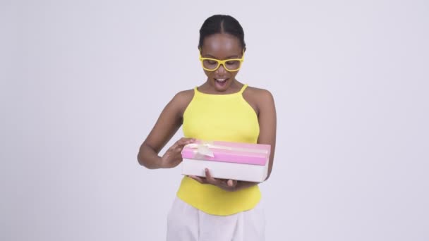Glückliche junge schöne Afrikanerin öffnet Geschenkbox und sieht überrascht aus — Stockvideo