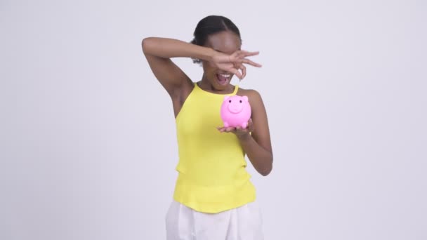 Glücklich junge schöne Afrikanerin zeigt Sparschwein — Stockvideo