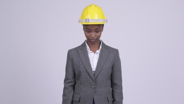 Giovane donna d'affari africana felice che indossa un cappello duro con le braccia incrociate — Video Stock