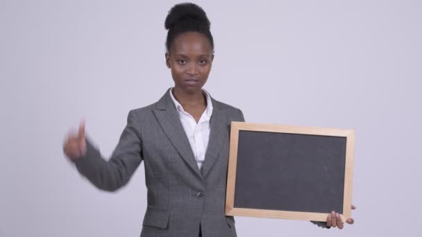 Молодая грустная африканская бизнесвумен держит доску и опускает большие пальцы — стоковое видео