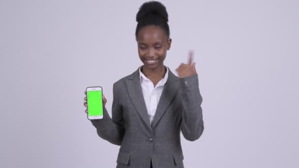 Joven feliz mujer de negocios africana mostrando el teléfono y dando pulgares hacia arriba — Vídeos de Stock