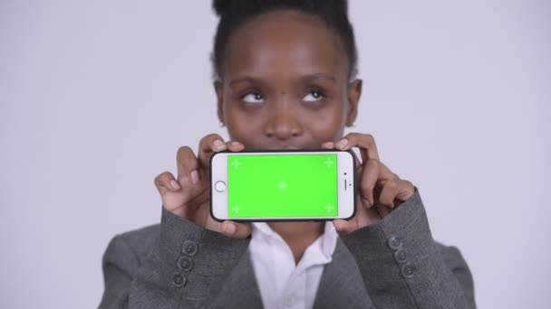 Rostro de joven feliz mujer de negocios africana pensando mientras muestra el teléfono — Vídeos de Stock