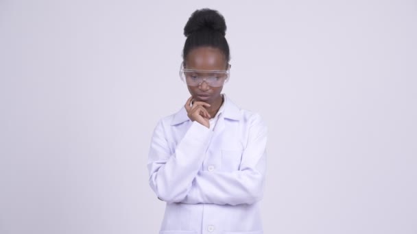 Young African woman doctor with protective glasses thinking and looking down — Stock Video