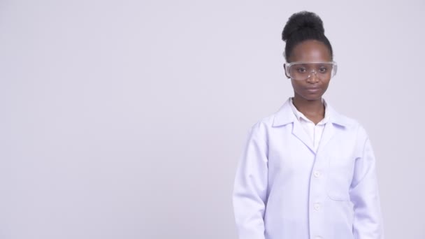 Jeune femme africaine heureuse médecin avec des lunettes de protection montrant quelque chose — Video