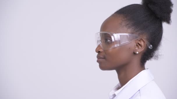 Profiel te bekijken van jonge Afrikaanse vrouw arts met een beschermende bril glimlachen — Stockvideo