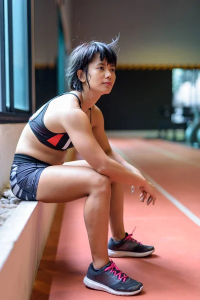 Młody piękny Asian kobieta siedzi i zrelaksować się w siłowni — Zdjęcie stockowe