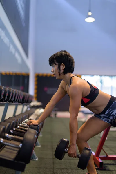 Młody piękny Asian kobieta robi hantle wiersza w siłowni — Zdjęcie stockowe