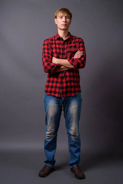 灰色の背景に立っている若い男の完全な長さの肖像画 — ストック写真